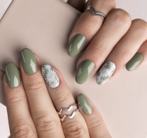 Beautiful womans hands with spring summer floral nail design. Trendy green color manicure close-up